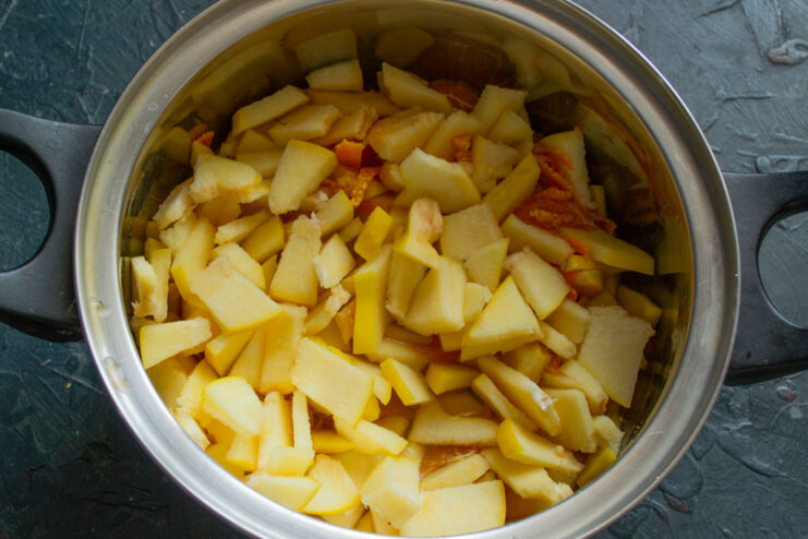 Mixing the Fruits: Adding Sliced Quince to the Mandarins Sliced quince being added to a pot with mandarin segments and peel.
