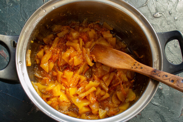 Finishing the Jam: Simmering Until Thick and Translucent The quince and mandarin jam simmering in a pot on the stove, thickening to its final consistency.