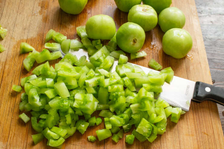 Finely Chopping Green Tomatoes for Jam Close-up of finely chopped green tomatoes on a cutting board.