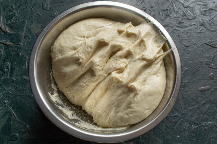 Second Rise for Extra Fluffy Dough The punched-down dough in a glass bowl, covered with plastic wrap for its second rise.