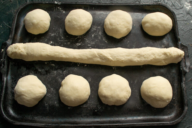 Shaping and Arranging Vatrushki and Baguette for Proofing Shaped raw dough buns and a small baguette arranged on a parchment-lined baking sheet.
