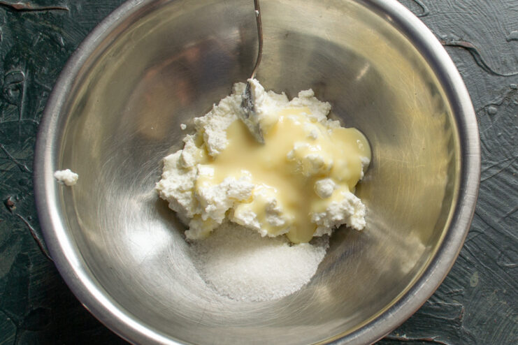 Preparing the Sweet Tvorog Filling A bowl with tvorog, sweetened condensed milk, and sugar being mixed for the filling.