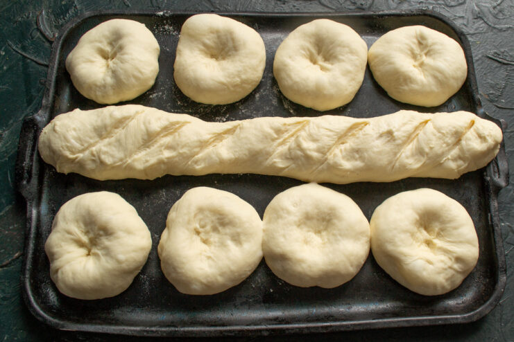 Creating Indentations for the Filling and Scoring the Baguette Making indentations in the proofed buns and scoring the baguette before baking.