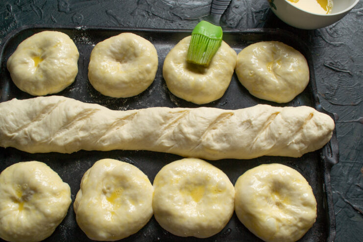 Applying Egg Wash for a Golden Finish Brushing the Vatrushki buns with egg wash before adding the filling.