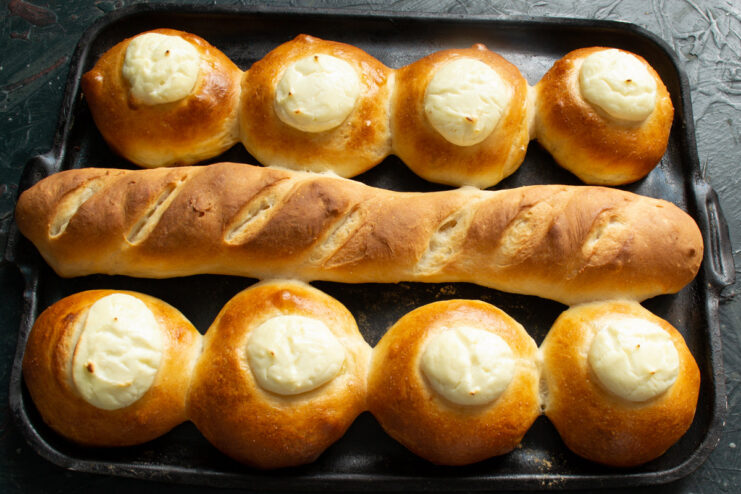 Golden Brown Vatrushki and Baguette Fresh from the Oven A baking sheet with perfectly baked, golden brown Vatrushki and a crusty baguette.