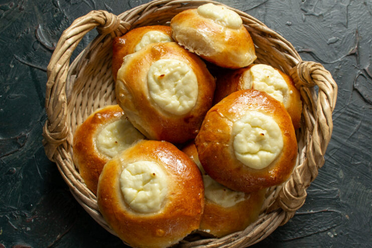 Enjoying Warm Vatrushki with Tea or Milk A plate of warm, glazed Vatrushki sweet cheese buns, ready to be served.