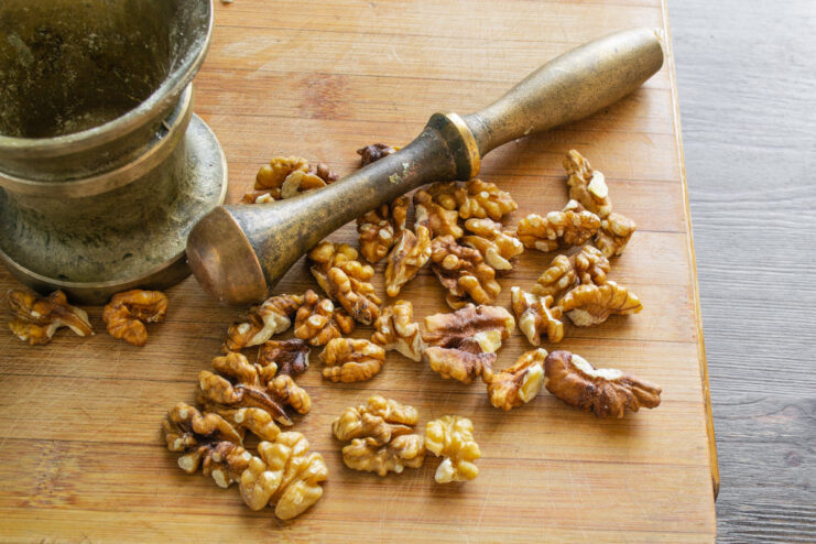 How to prepare walnuts for salad: toasting and chopping. Toasted walnuts being finely chopped on a cutting board.