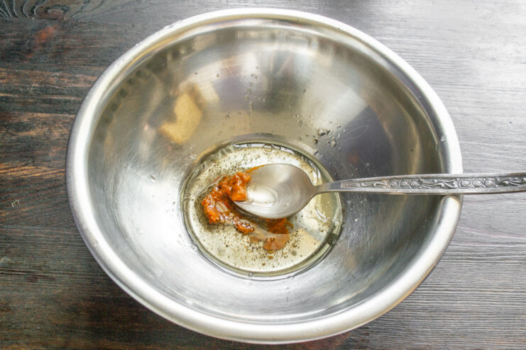 Making a simple and flavorful walnut dressing for the salad. Ingredients for the salad dressing, including olive oil and lemon juice, in a mixing bowl.