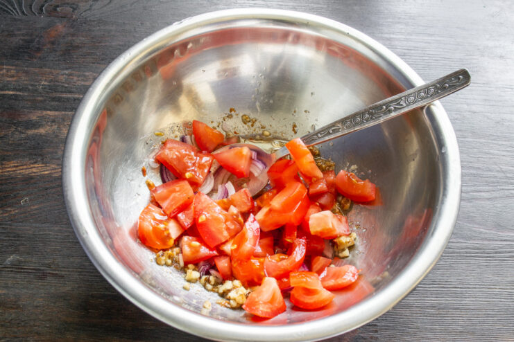 Dicing fresh tomatoes for the walnut and tofu salad. Fresh red tomatoes being diced into small cubes for the salad.