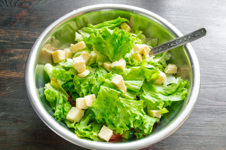 Cutting tofu into bite-sized cubes for the vegan salad. A block of firm tofu being cut into small, even cubes on a cutting board.
