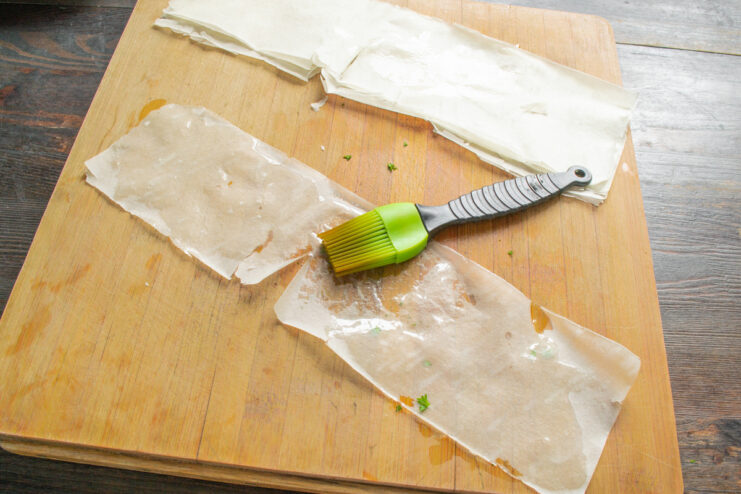 How to Prepare Phyllo Dough for Samsa A strip of thin phyllo dough being cut to the correct size for making samsa.