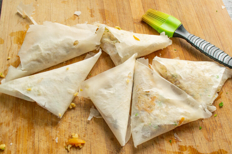 Shaping Multiple Samsa Pastries A row of perfectly folded, uncooked triangular samsa pastries ready for baking.