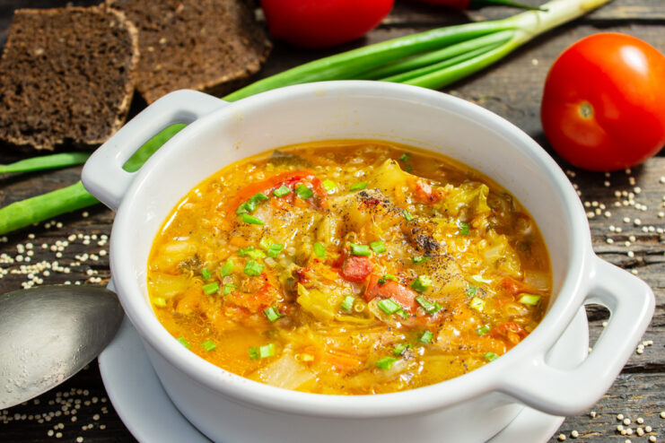 A bowl of ready-to-eat vegetarian quinoa soup, garnished with fresh herbs.