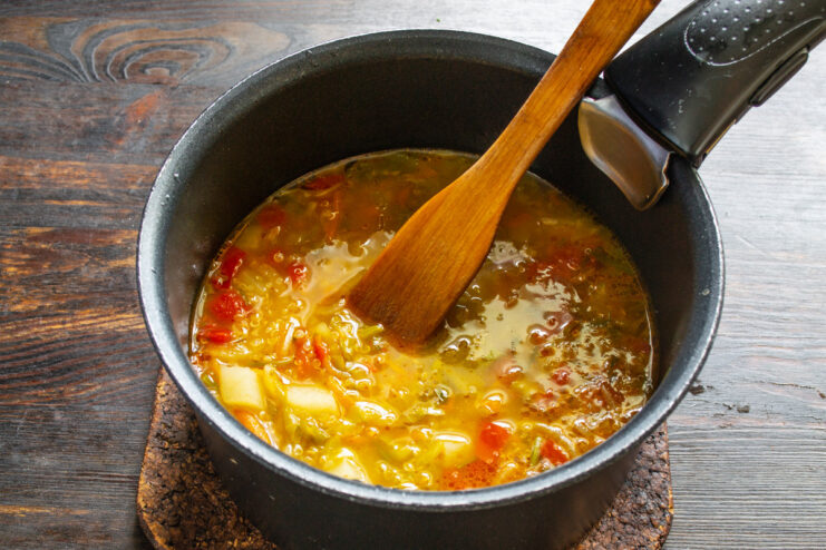 Simmering the soup until all ingredients are tender A pot of soup simmering on the stove with a lid on.