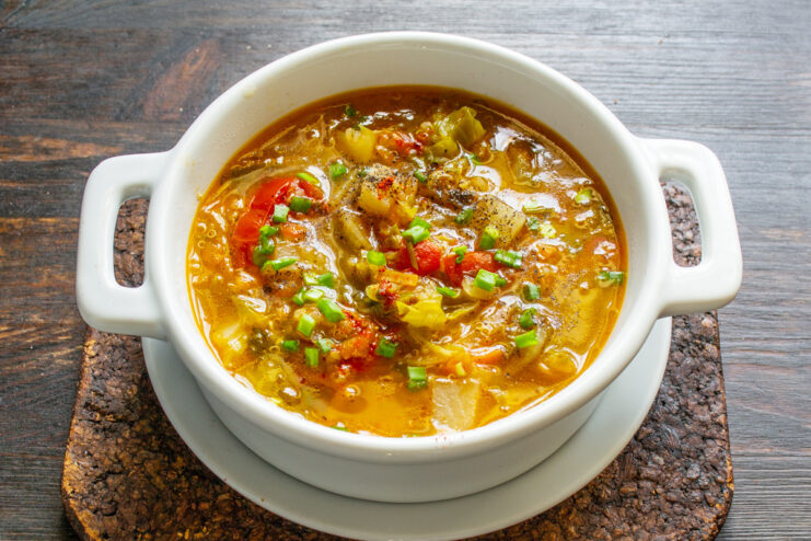 Serving the delicious homemade vegetarian soup A finished bowl of vegetarian quinoa soup garnished with chopped green onions.