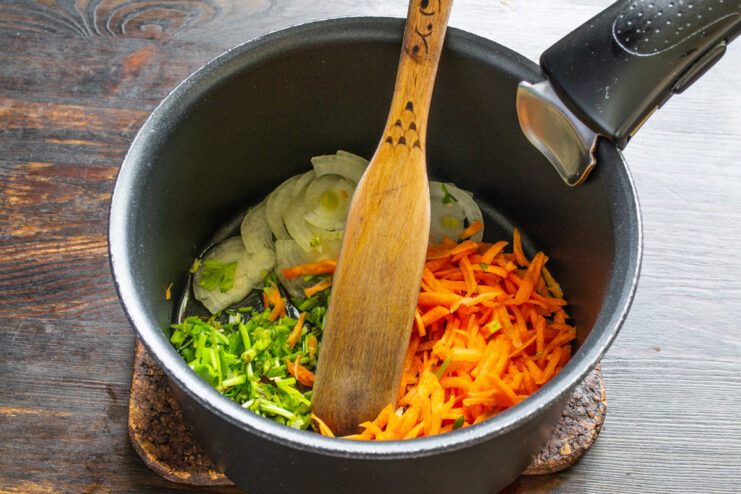 Sautéing the vegetable base for the soup Chopped onions, carrots, and celery being added to a pot with hot oil.