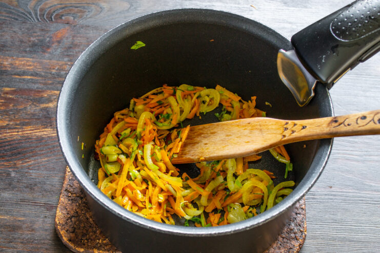 Creating the soffritto base for a flavorful soup Sautéing a mix of chopped vegetables in a pot to soften them.