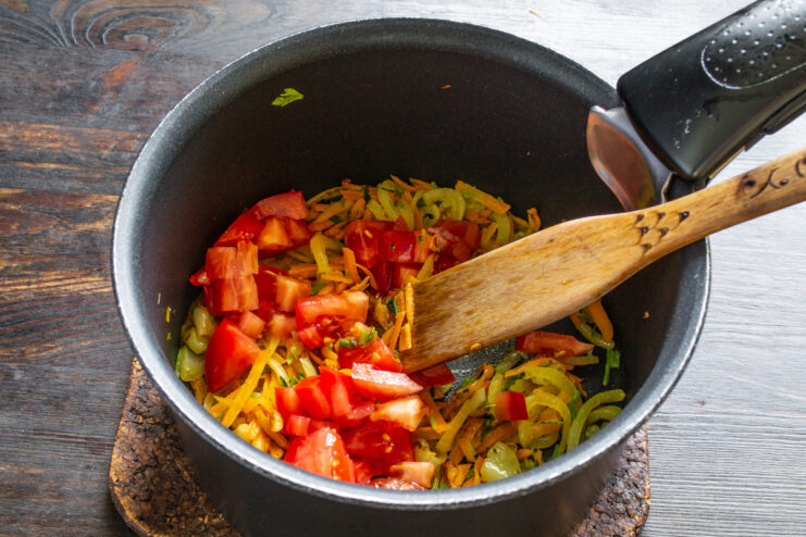 Adding fresh tomatoes for richness and flavor Diced fresh tomato being added to the sautéed vegetables in the pot.