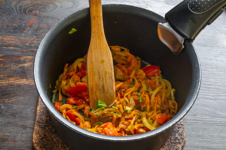 Seasoning the soup with aromatic Herbes de Provence A hand sprinkling a teaspoon of Herbes de Provence into the pot with vegetables.