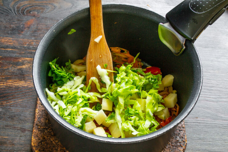 Adding fresh cabbage for texture and nutrients Thinly shredded early cabbage being added to the soup pot.