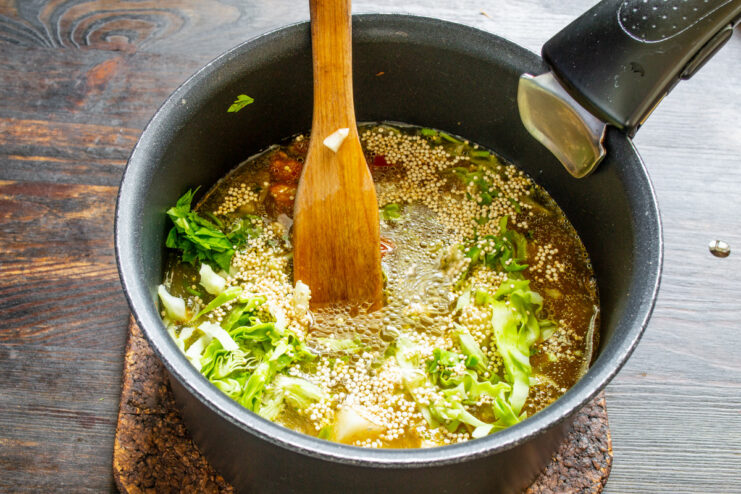 Adding water to cook the soup Pouring water into the pot with all the vegetables and quinoa.
