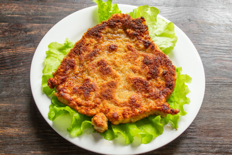 Serving the Freshly Cooked Pork Schnitzel A freshly cooked, golden Viennese pork schnitzel on a plate, ready to be served.