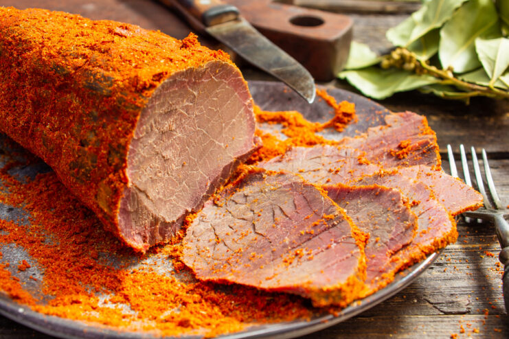 Sliced homemade boiled beef ham served on a wooden board, ready to eat.