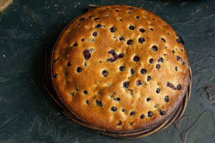 Step 11: Cooling the freshly baked cake The golden-brown, freshly baked blackcurrant cake cooling on a black wire rack.