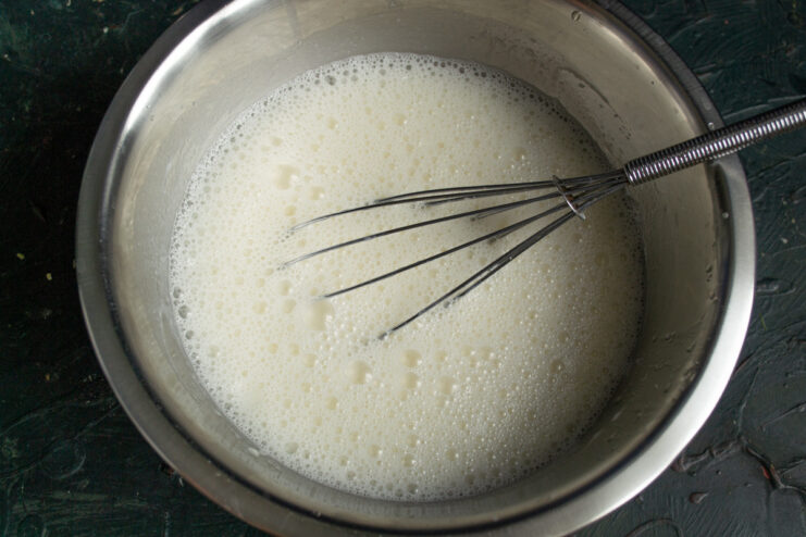 Step 4: Blending the wet ingredients until smooth Using an immersion blender to mix the wet ingredients for the cake batter in a glass bowl.