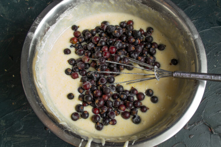 Step 7: Preparing fresh blackcurrants for the cake A metal colander filled with freshly washed, ripe blackcurrants.