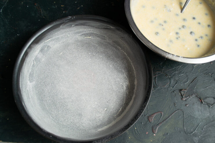 Step 8: Preparing the baking pan A round metal baking pan being greased with butter and dusted with flour.