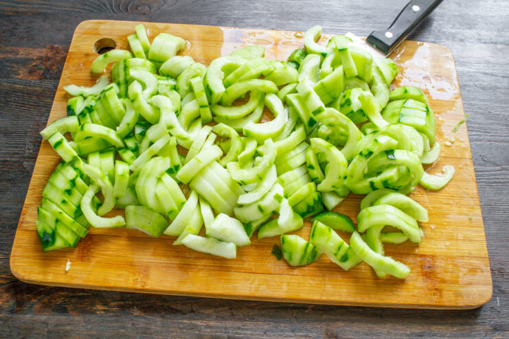 Slicing the Prepared Cucumbers into Half-Centimeter Pieces A pile of freshly sliced, peeled, and seeded cucumber pieces on a cutting board.