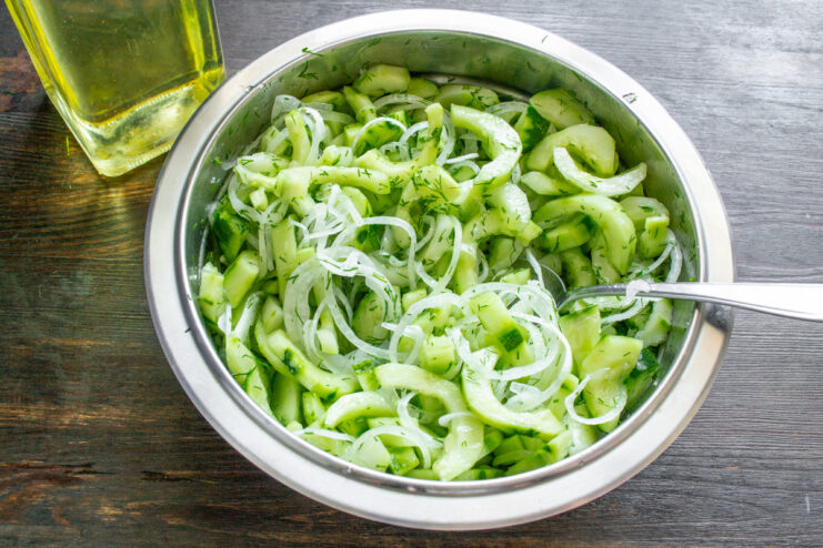 Letting the Salad Macerate to Release Juices A bowl of cucumber salad marinating, showing the liquid that has been released from the vegetables.