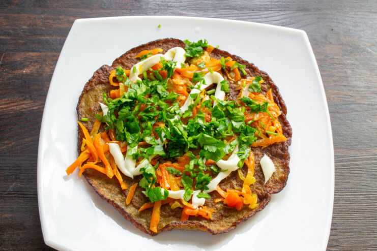 Assembling the savory liver cake, layer by layer Assembling the liver cake: a liver pancake topped with sautéed vegetables and mayonnaise.