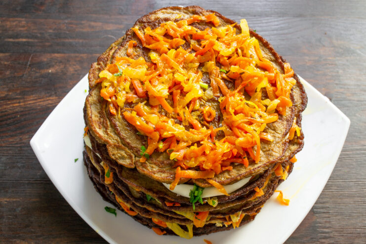 Building the layers of the savory beef liver cake A multi-layered savory liver cake being assembled on a plate.