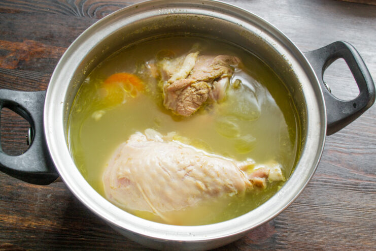 Simmering the broth to extract all the flavor from the turkey and vegetables. A pot of turkey broth simmering on the stove, with vegetables and spices visible.