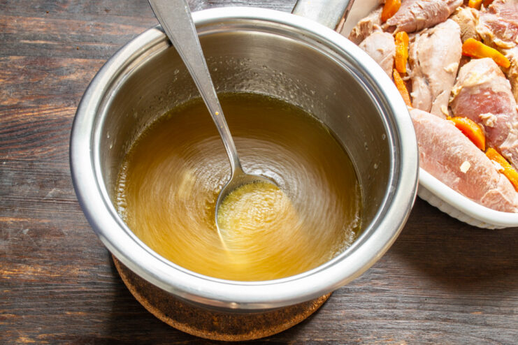Combining the gelatin with the broth to create the aspic base. Pouring dissolved gelatin into a pot of warm turkey broth and stirring.