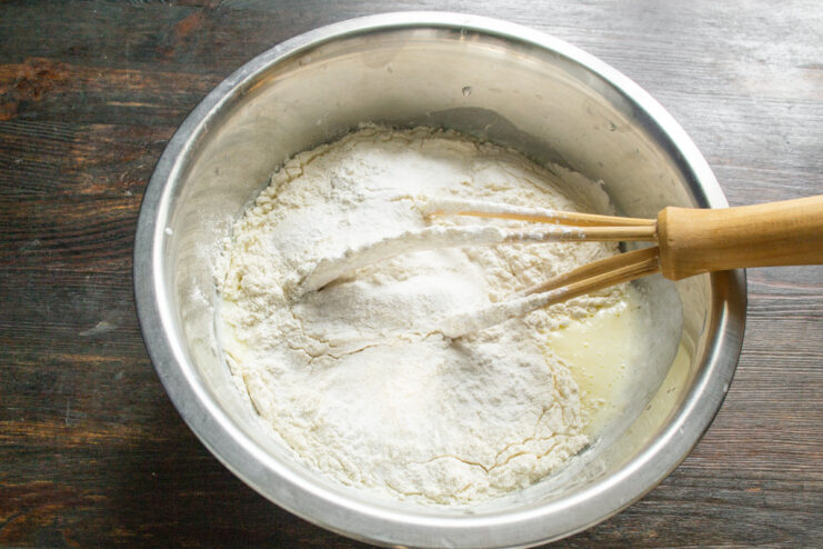 Sifting dry ingredients into the wet mixture to ensure a smooth, lump-free batter. Sifting flour and other dry ingredients into the bowl with the wet batter mixture.