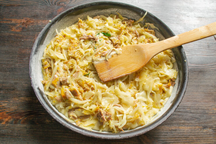 Spreading the cabbage and tushonka filling evenly over the first layer of batter. Spreading the cabbage and meat filling over the batter in the baking pan.