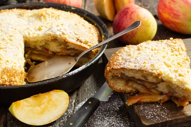 A slice of apple batter pie with a streusel topping on a plate.