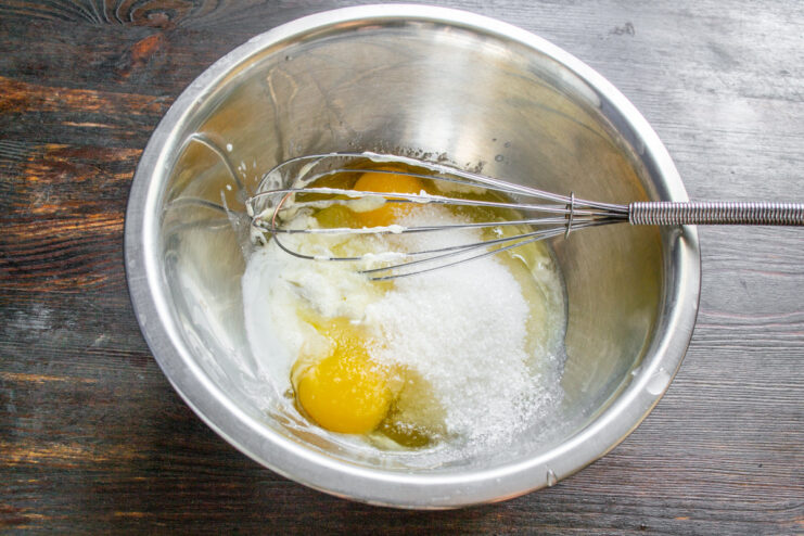 Step 2: Adding sugar and vanilla to the batter Adding sugar and vanilla sugar to the wet ingredients in a bowl.
