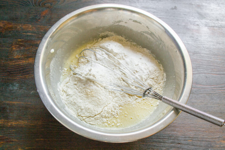 Step 3: Adding the dry ingredients to the batter Sifting flour, baking soda, and baking powder into the batter.