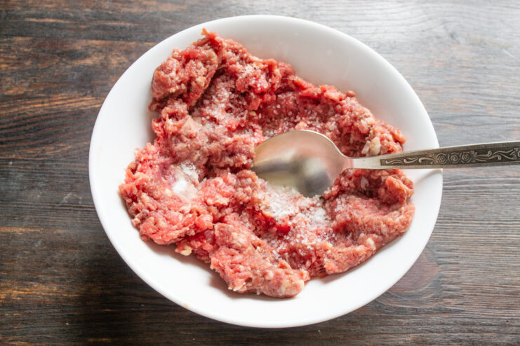 Start by Seasoning the Ground Beef A bowl of lean ground beef being seasoned with salt to prepare the patties.