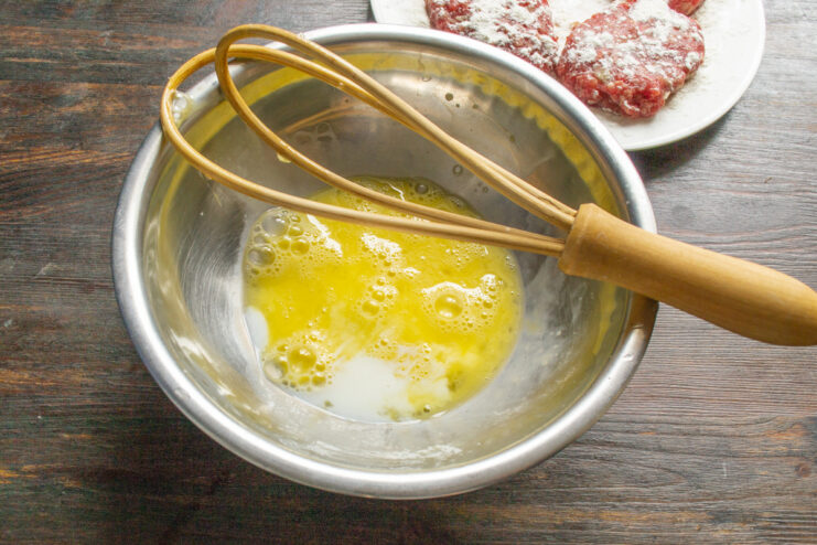 Preparing the Egg and Milk Mixture for the Bread An egg cracked into a wide bowl with milk, ready for whisking.