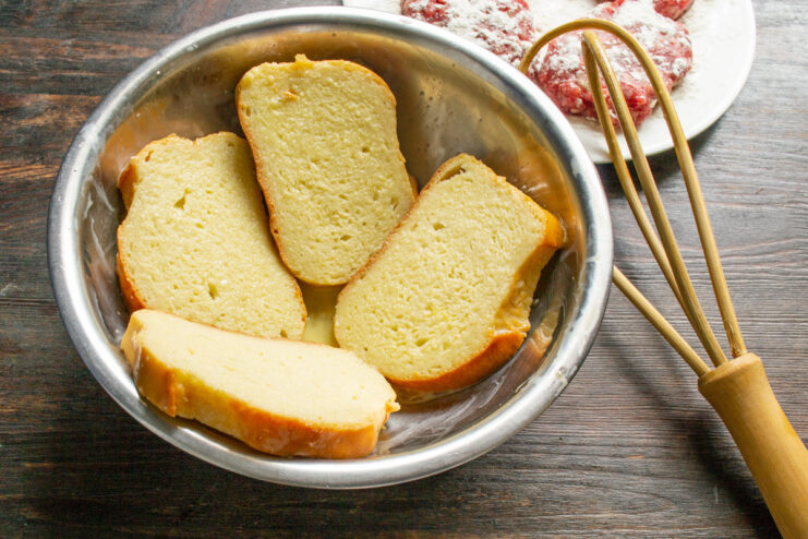 Soaking the Bread for a Golden, Crispy Finish Thick slices of white bread soaking in an egg and milk mixture in a bowl.