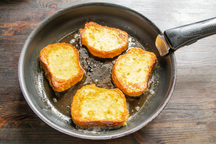Frying the Soaked Bread Until Golden Brown Slices of egg-soaked bread being fried in a pan until perfectly golden brown.