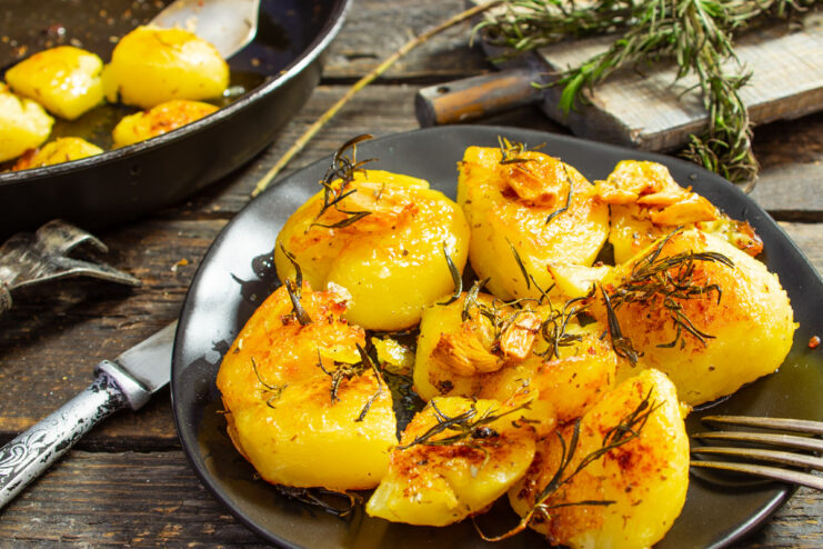 A pan of golden roasted potatoes with rosemary and garlic, ready to serve.