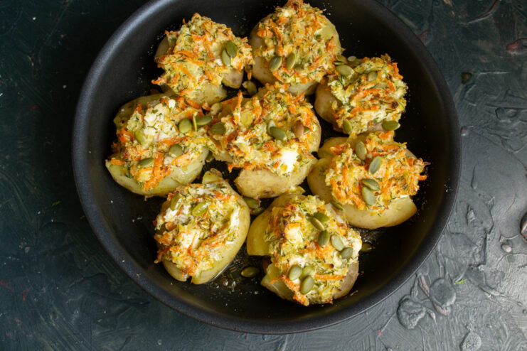 Baking to Golden Perfection A skillet with stuffed potatoes, sprinkled with pumpkin seeds, ready to be baked in the oven.