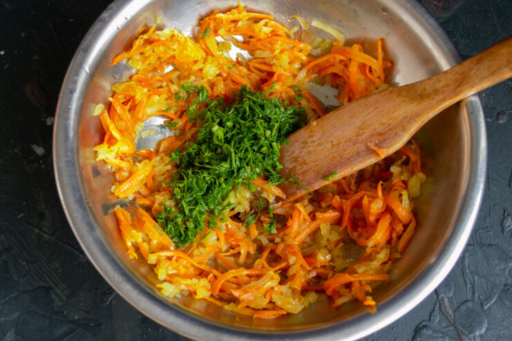Adding Fresh Herbs for Flavor Chopped fresh dill being added to the cooked carrots and onions in a bowl.