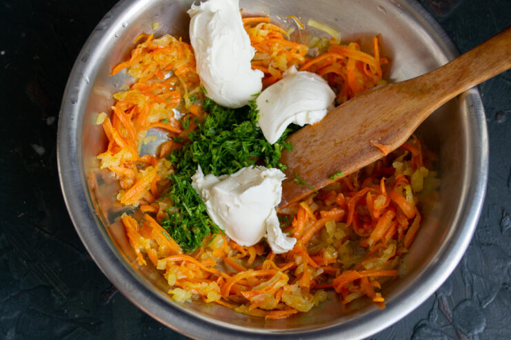 Creating the Creamy Cheese Filling A block of cream cheese being added to a bowl with sautéed vegetables and herbs.